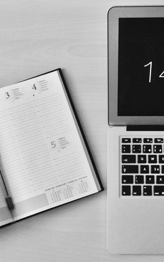 Flat Lay Photography of Unfold Book Beside Macbook